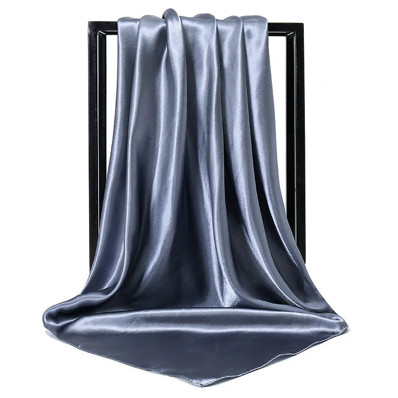 Una bufanda de satén azul y sedosa drapeada colgada en un soporte negro.