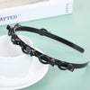 A black multi-layer braided hair headband clip resting on a white saucer.