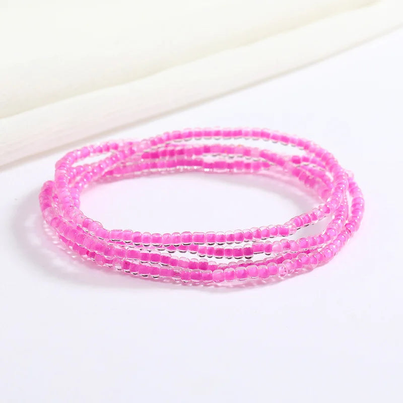 Pulsera de cadena corporal de cuentas rosas apilada sobre fondo blanco.