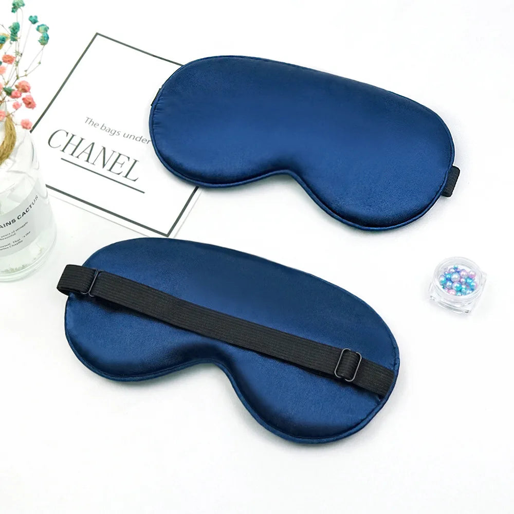 A dark blue silk sleep mask is shown next to a box labeled Chanel.