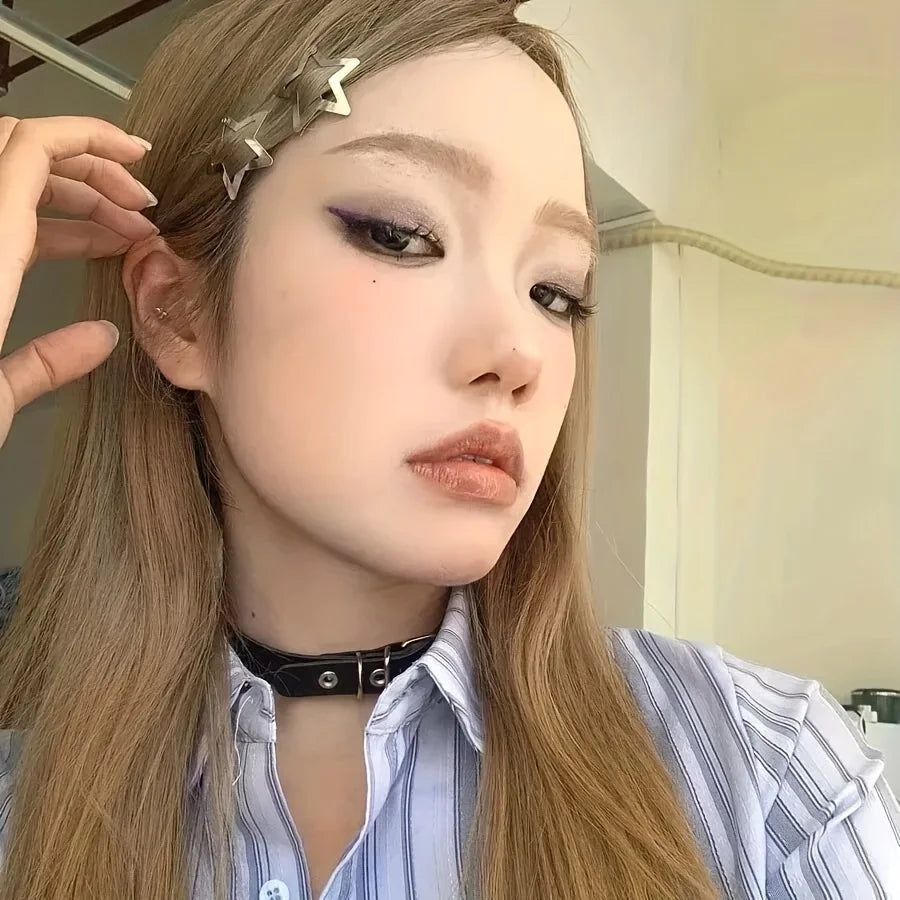 A close-up of a woman with long blonde hair wearing silver star metal snap hair clips and a striped shirt.