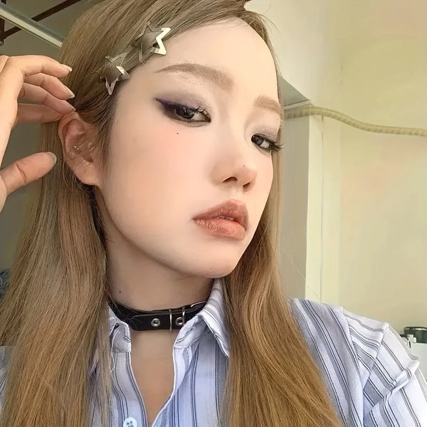 A close-up of a woman with long blonde hair wearing silver star metal snap hair clips and a striped shirt.