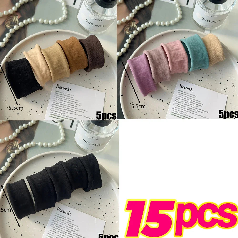 A collection of five colored elastic hair bands in various shades of pink, beige, and teal are displayed on a white plate.