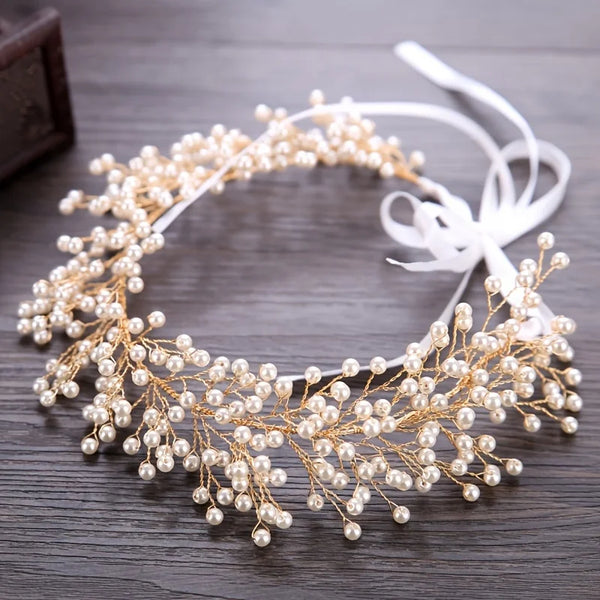 A delicate gold pearl hair vine headband with white ribbon, suitable for special occasions.