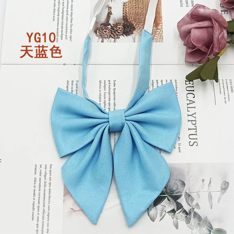 A light blue solid cotton bow tie shown against a white background with floral and natural elements.