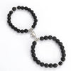 A pair of black natural stone heart couple bracelets with silver accents.