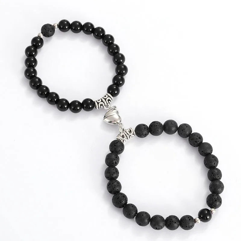 A pair of black natural stone heart couple bracelets with silver accents.