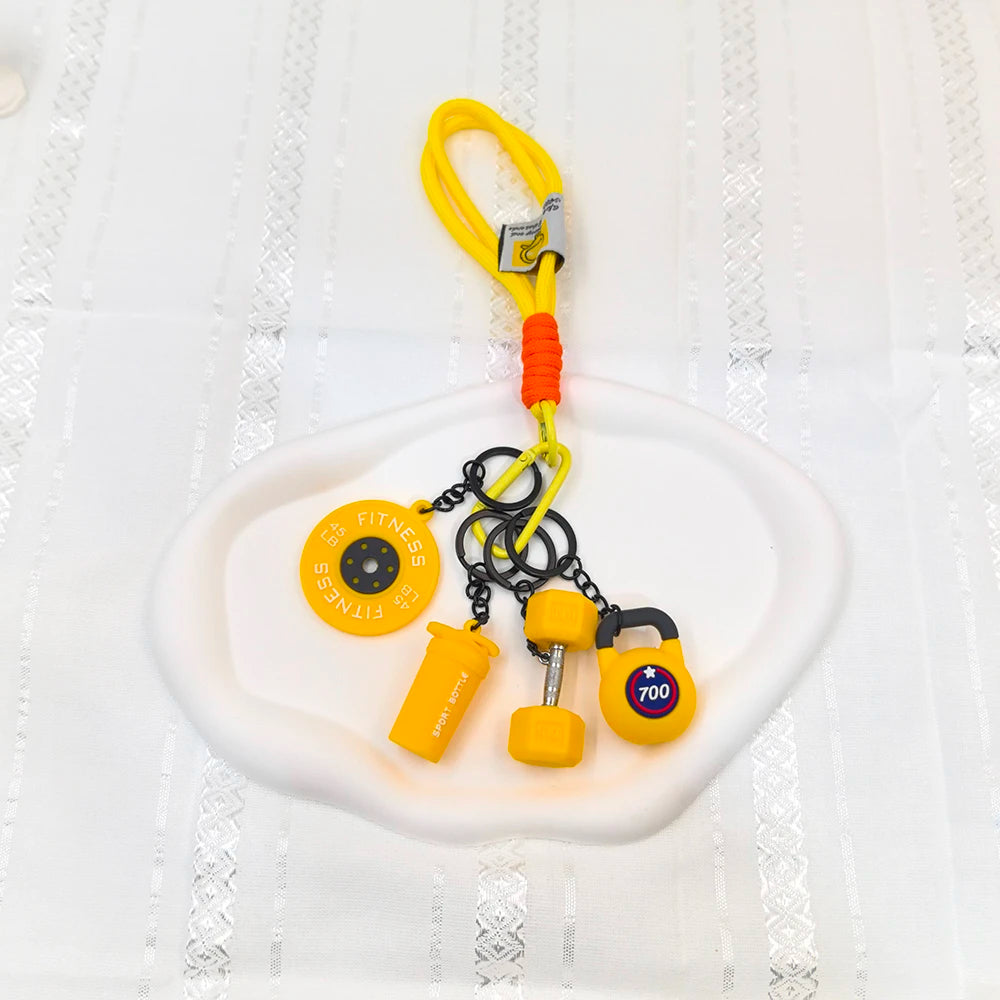 A set of yellow fitness keychains and weightlifting accessories including a yellow dumbbell and various metal rings on a whit