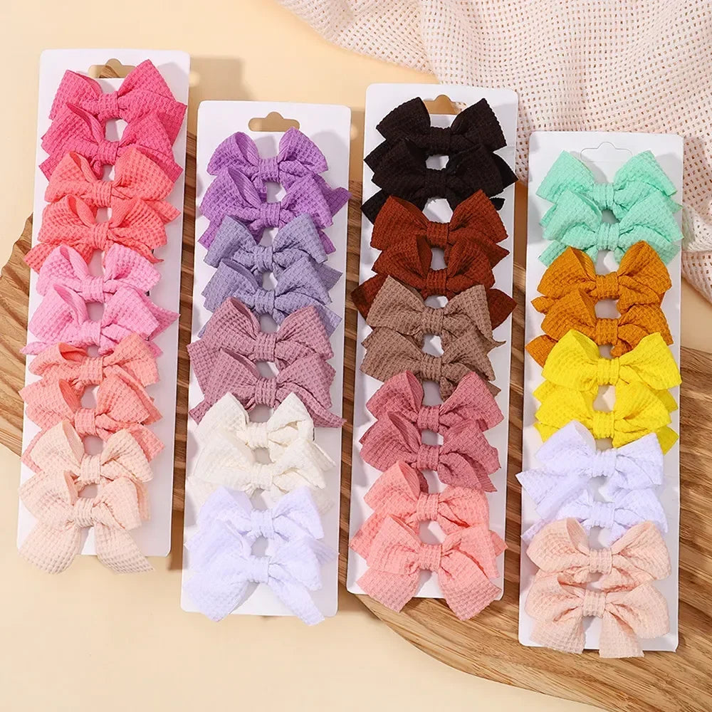 A collection of handmade ribbon bow hair clips in various shades of pink, purple, orange, yellow, and white.