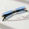 A pair of trendy frameless rectangular sunglasses with blue-tinted lenses and gold accents resting on a white surface.