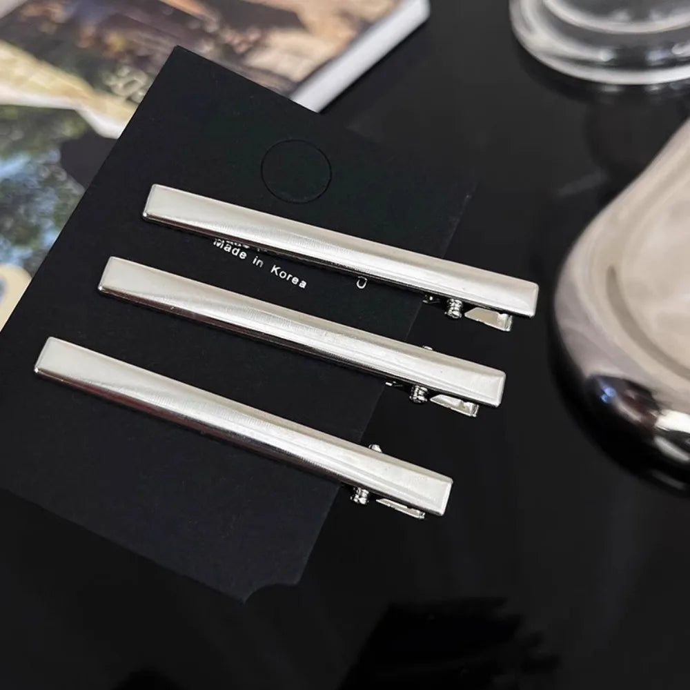 A set of three vintage silver Y2K metal hair clips displayed on a black surface.