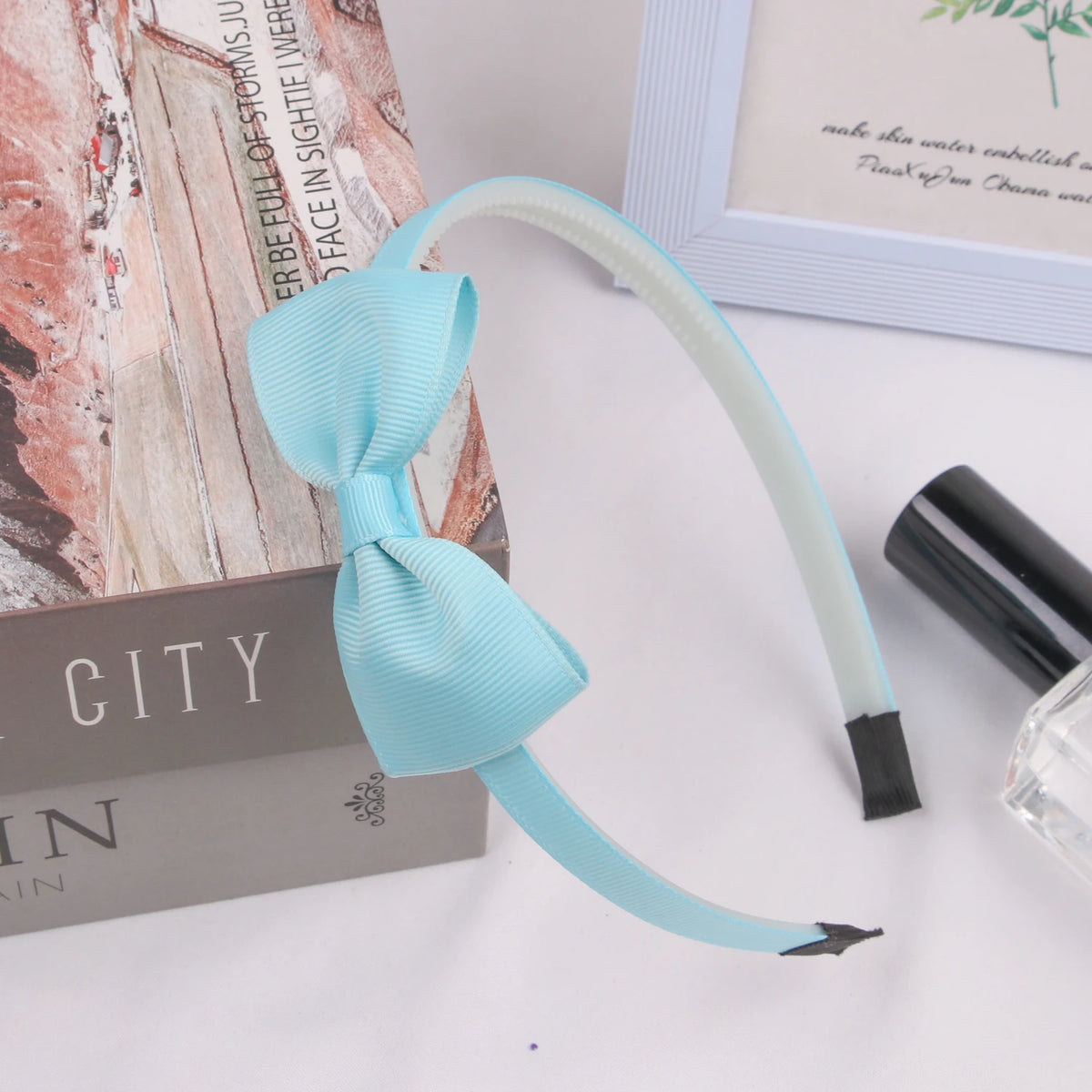 Light blue grosgrain ribbon hair bow with a thin elastic band displayed on a wooden surface.