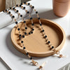 Gold and black crystal bead lanyards and chains displayed on a wooden tray.