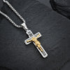 Colgante de cruz de Jesús chapado en oro con placa INRI grabada, colgando de una cadena de plata, sobre una piedra oscura.