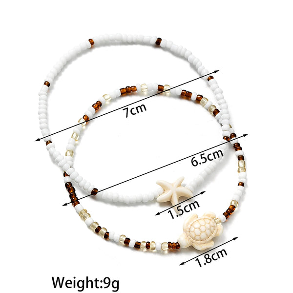 White beaded bracelet featuring starfish and turtle charms, measuring 7cm in length.
