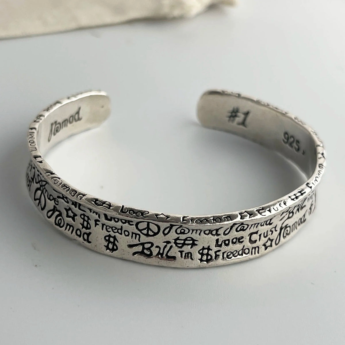 A sterling silver charm bracelet with engraved words and the number one on a white background.
