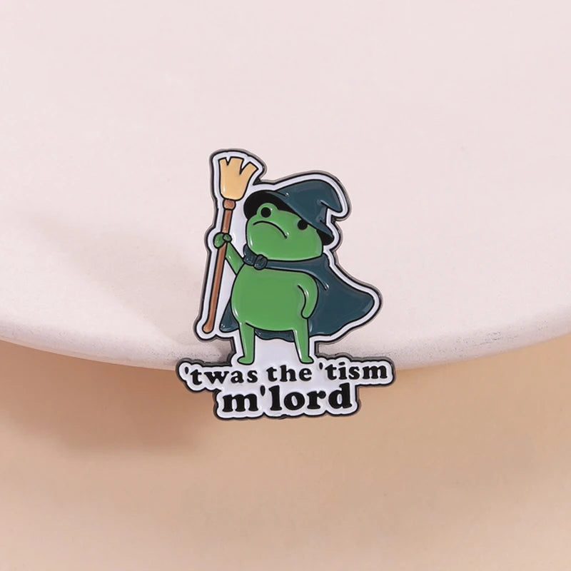 Insignia de esmalte con un personaje de rana verde sosteniendo una varita amarilla y el texto "was the tism mlord"