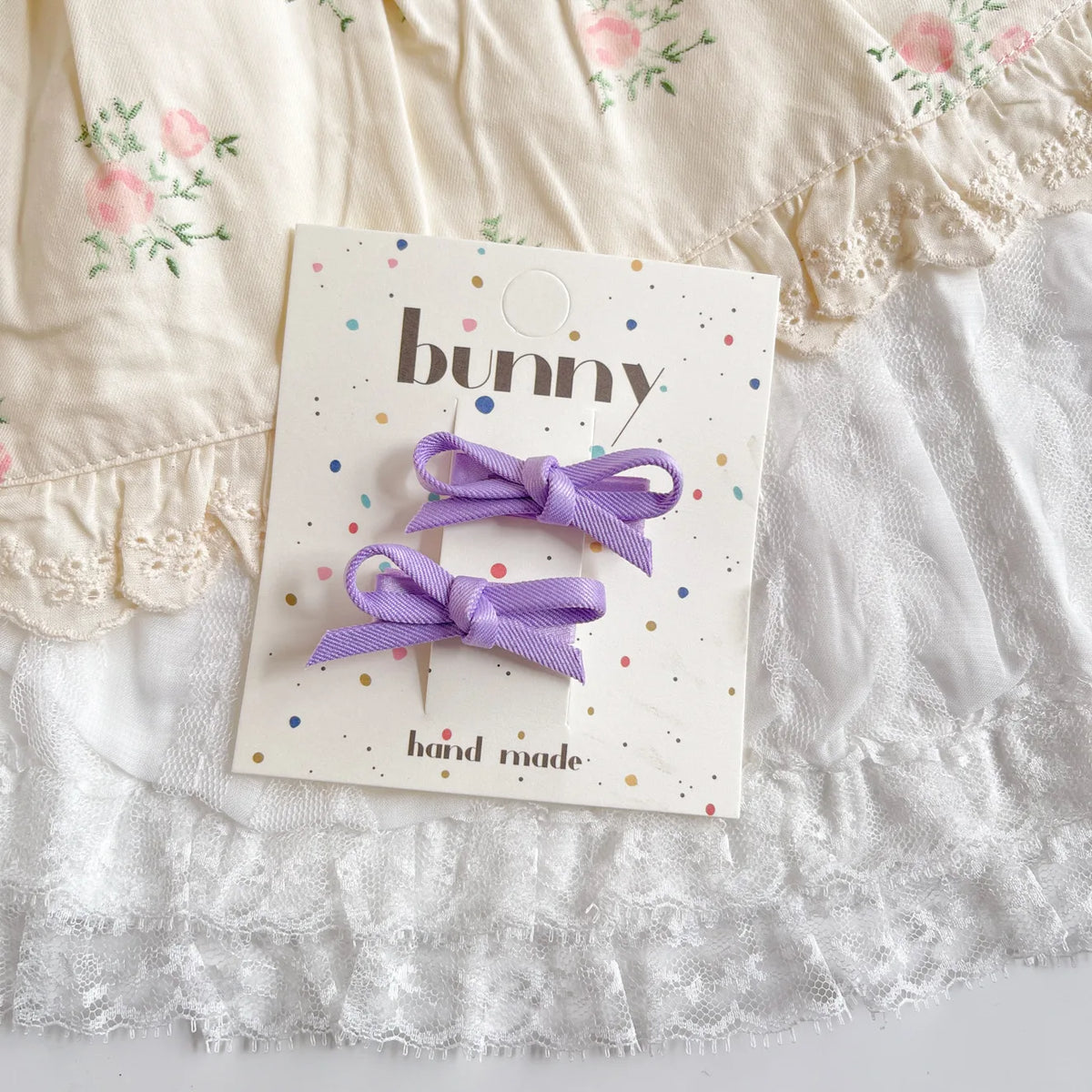Un set de pinces à cheveux en nœud violet pour filles, présenté sur une carte produit blanche.