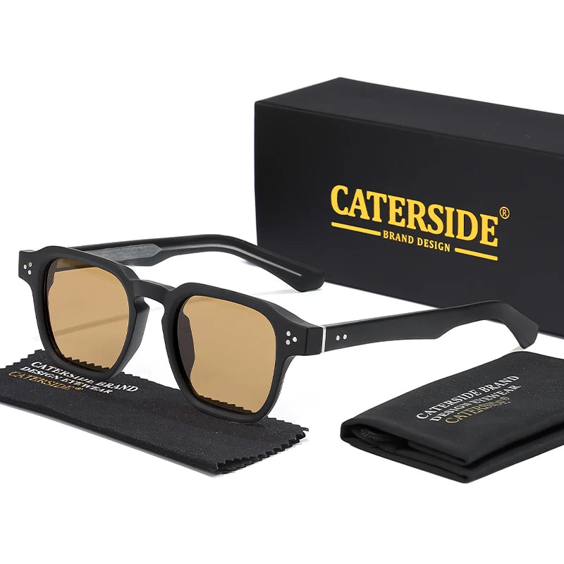 Ein Paar schwarze quadratische modische Sonnenbrille mit goldfarbenen Linsen, präsentiert neben der Markenbox und dem Etui.