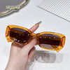 A hand holds a pair of amber-colored polarized fashion sunglasses against a white background.