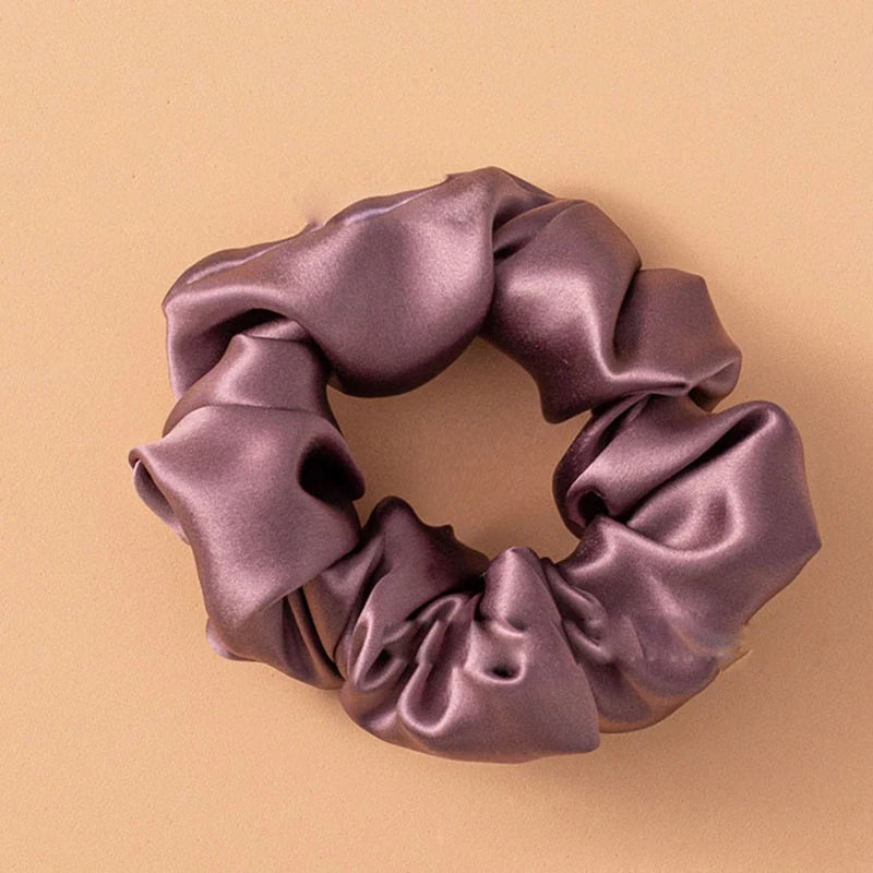 Primer plano de una liga para el pelo de seda morada oscura atada en forma de lazo decorativo.