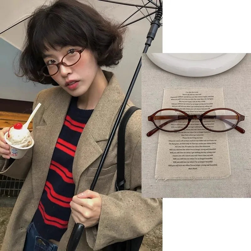 Une femme portant des lunettes ovales rétro Y2K et un manteau beige, regardant directement l'appareil photo.