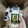 Eine Hand hält eine Flasche Luxfume Lace Glue, eine klare Flüssigkeit mit schwarzem und goldenem Etikett, in einer Kartonverp