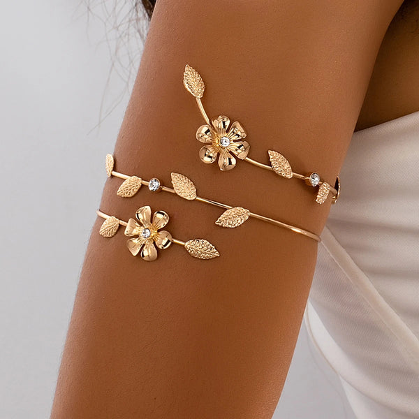 Gold floral vine arm bracelet worn on a person's wrist.