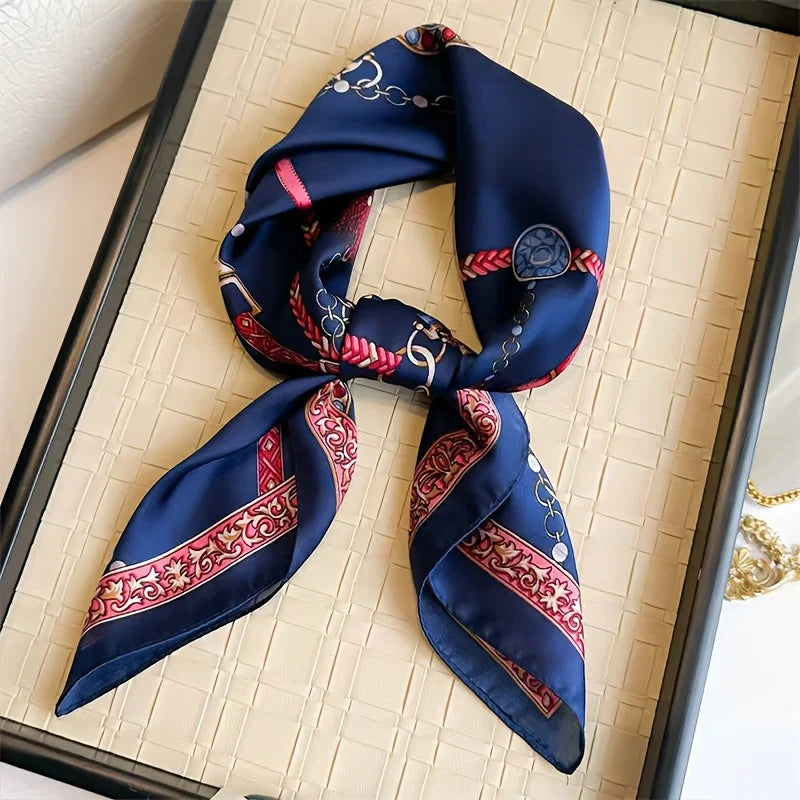 A dark blue silk scarf with red and gold embroidery tied in a knot, displayed against a light background.
