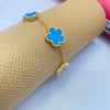 A gold plated stainless steel double-sided petal bracelet with blue floral charms is displayed on a beige cylindrical object.