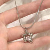 A silver heart-shaped necklace with a zircon stone is displayed on a person's hand.
