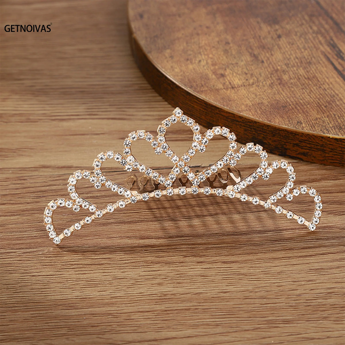 A sparkling crystal princess tiara hair comb for women displayed on a wooden surface.