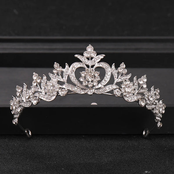 A silver crystal rhinestone bridal tiara headpiece with intricate floral and heart designs.