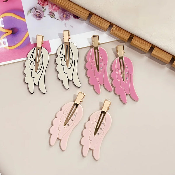 A set of pink and white angel wing hair clips and barrettes displayed on a light background.