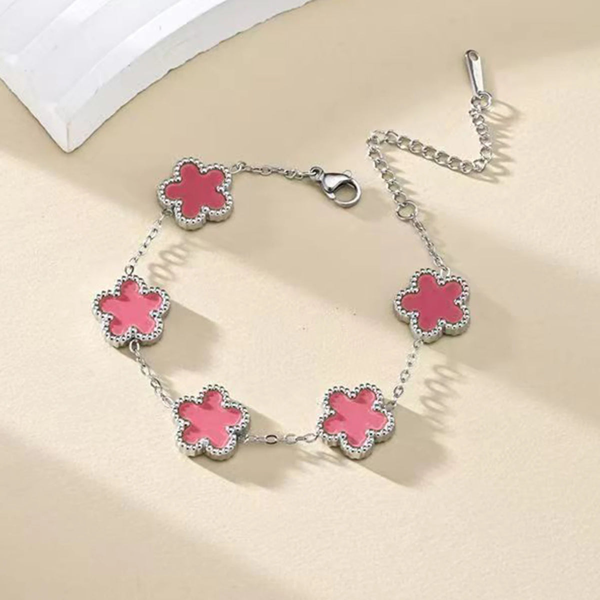 A silver gold plated stainless steel bracelet featuring multiple pink floral petals.
