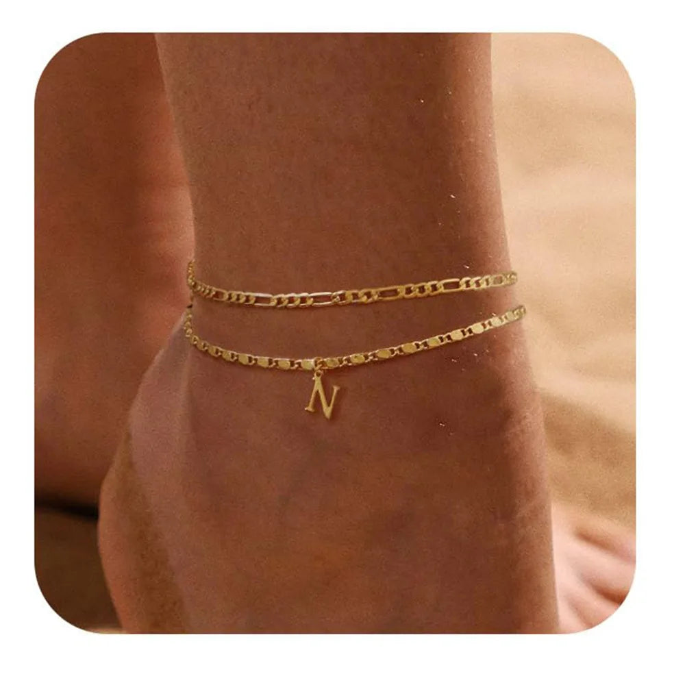 Primer plano de una pulsera de adorno dorada vintage con una inicial N, puesta en la muñeca.