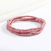 Una delicada pulsera de cadena de cuentas rosas sobre una superficie blanca.
