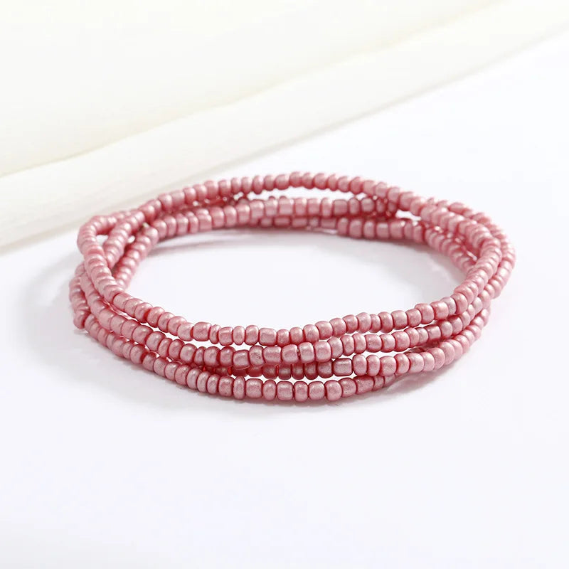 Una delicada pulsera de cadena de cuentas rosas sobre una superficie blanca.