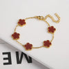Pulsera de acero inoxidable chapada en oro con pequeños charms florales marrón rojizo.