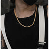 A close-up of a dainty gold rope chain necklace worn around the neck against a black shirt.