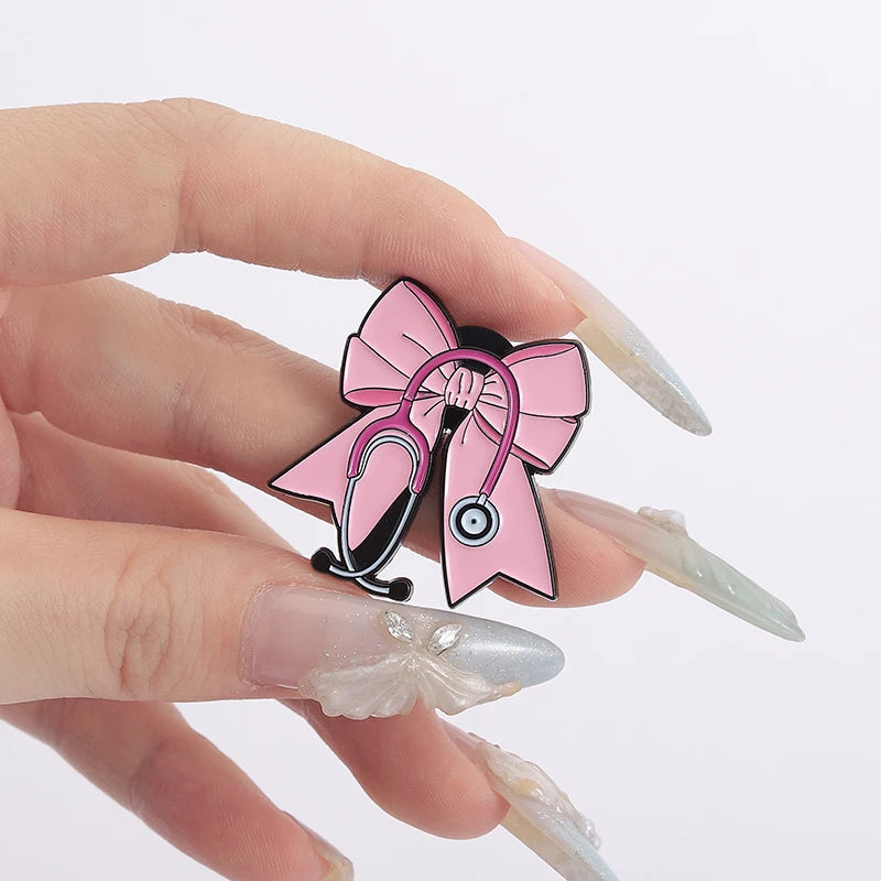 Pin de estetoscopio de esmalte con lazo rosa mostrado en una mano