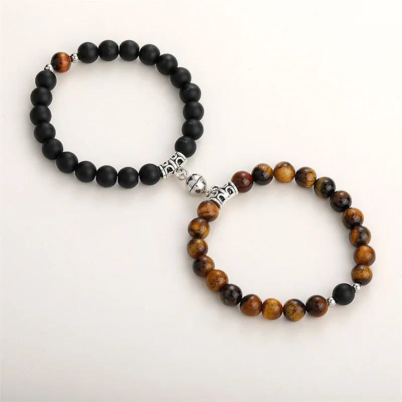 A pair of natural stone heart couple bracelets featuring black and amber beads and silver accents.