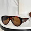 A pair of oversized tortoiseshell sunglasses with dark brown lenses resting on a white surface.