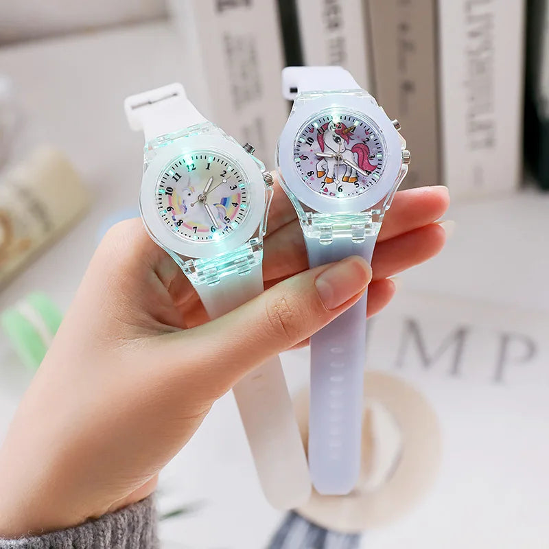A hand holds a cute unicorn fashion watch for girls and women with a light blue strap and clear face.