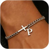 A close-up of a silver stainless steel Cuban chain bracelet featuring an engraved cross and the letter P on a person's wrist.