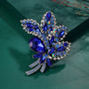 Broche florale en cristal argenté scintillant avec des pierres bleues profondes et des accents clairs.