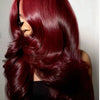 A close-up of a woman with long, wavy burgundy hair looking over her shoulder.
