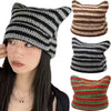 A close-up of a woman wearing a black and white striped crocheted cat ears beanie hat.