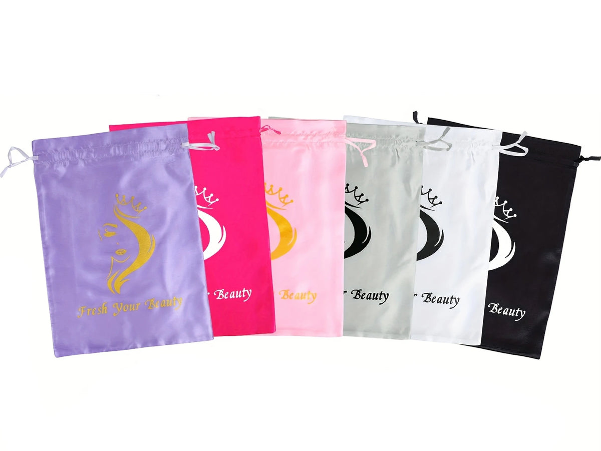 A row of colorful satin drawstring bags for storing wigs and hair extensions in purple, pink, green, and black.