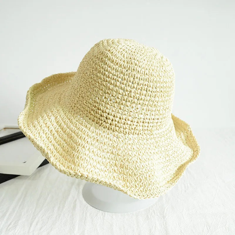 A light yellow hand-woven straw visor hat is displayed on a white surface.